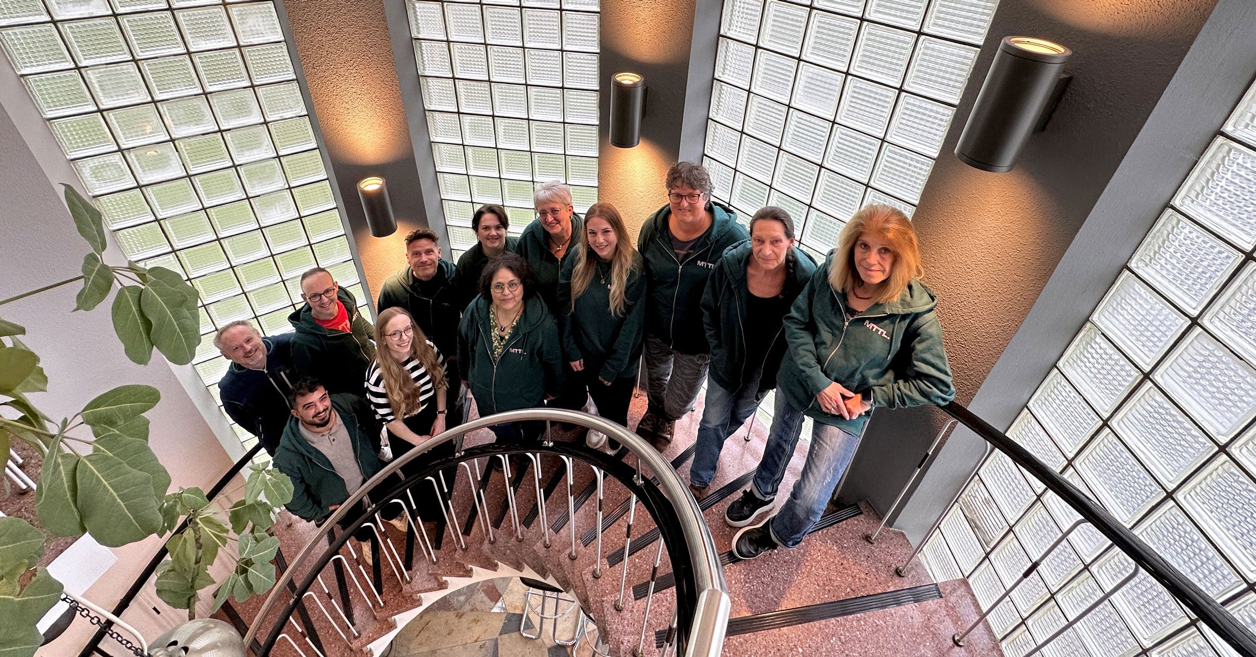 Gruppenfoto der suprima Mitarbeitenden auf der offenen Treppe im Treppenhaus.